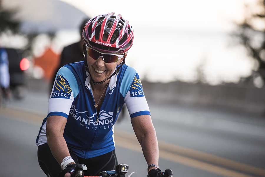 Women biking, smiling, on highway by coast