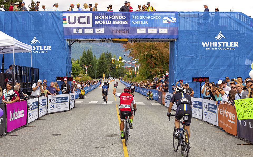 Riders cross the finish line to a huge crowd cheering